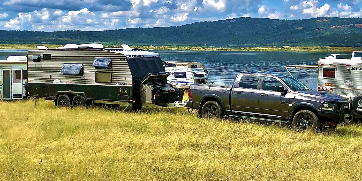 The Total Home Loan Options caravan and tow vehicle parked by a lake